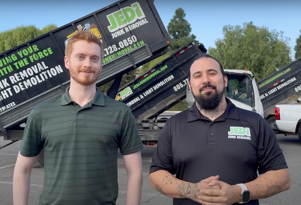 Two members of the Autopilot team standing in front of junk removal trucks